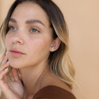 A woman with her hand on her face, elegantly showcasing the Duo Birthstone Studs—an ideal bridesmaids gift.