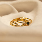 The Black Abyss Ring Set features three gold dainty bands adorned with black gemstones and small diamonds, shown on a soft beige fabric background.