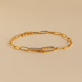 The Pave Link Chain Bracelet features elongated gold links and a crystal-encrusted clasp, making it an eye-catching statement piece, shown here on a beige background.