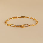 The Pave Link Chain Bracelet features elongated gold links and a crystal-encrusted clasp, making it an eye-catching statement piece, shown here on a beige background.