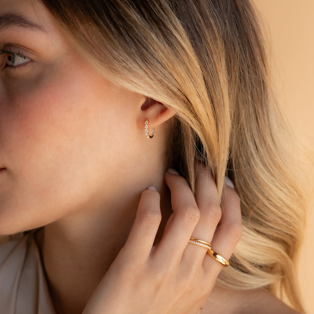Blonde woman gently touching her hair while wearing Inside Out Diamond Huggies in Sterling Silver.