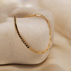 Black Diamond Tennis Bracelet—an eye-catching statement piece featuring black stones, showcased on a smooth beige stone with a soft, neutral backdrop.