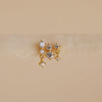 The Triple Diamond Studs Set features gold stacking earrings, each with three clear gemstones reminiscent of diamond drops, showcased on a soft neutral background.