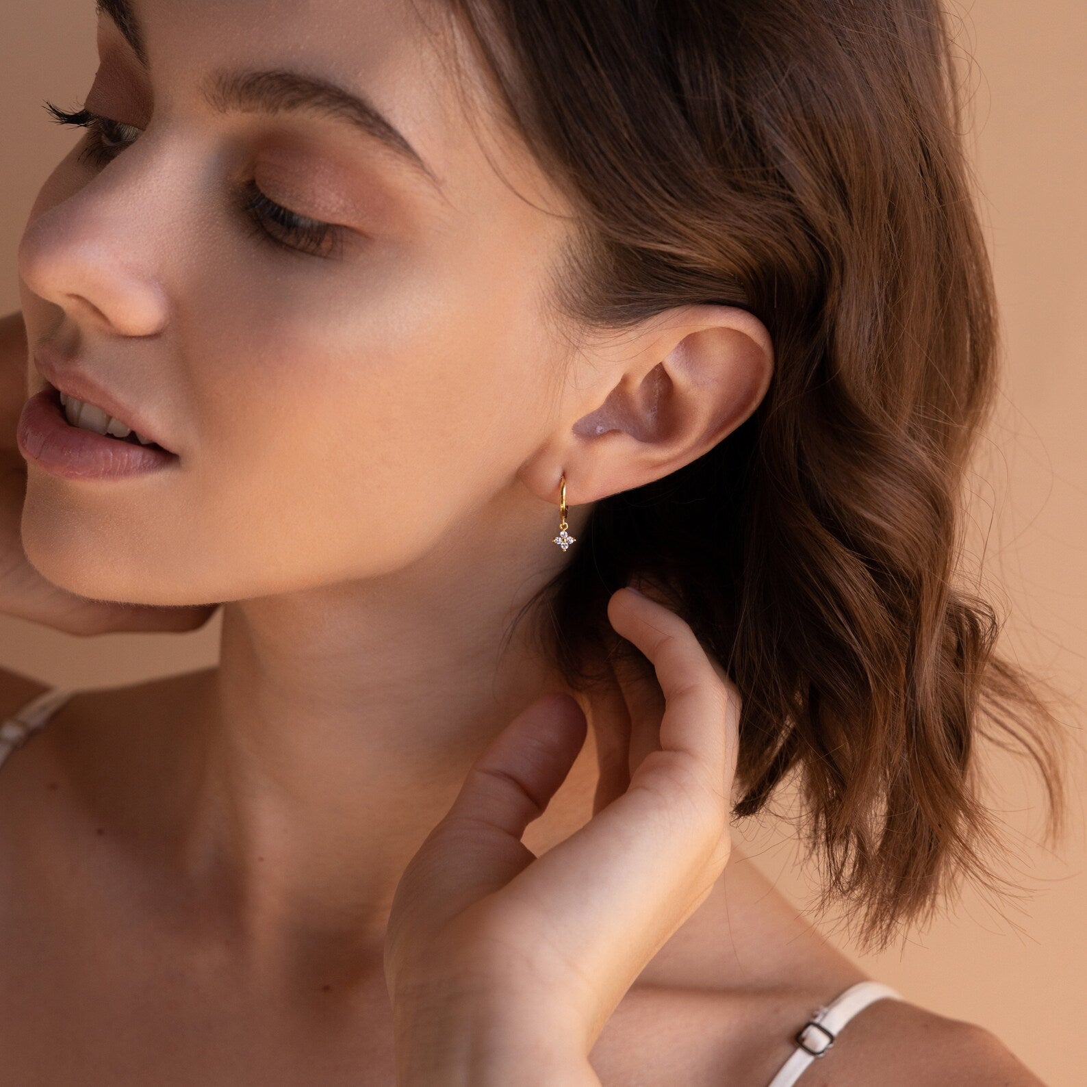 A woman poses with her head turned to the side, wearing a gold Diamond Flower Huggie in one ear
