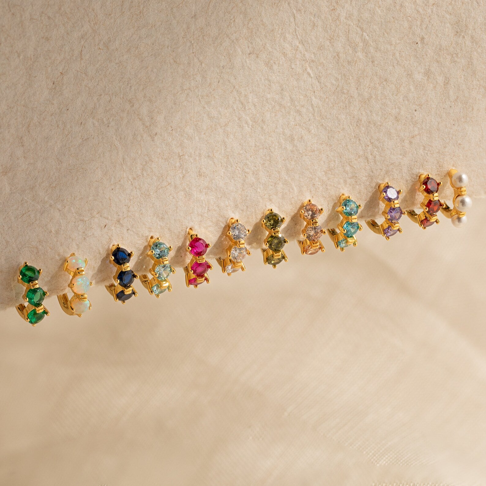 The Triple Ruby Huggies feature three sparkling rubies set in gold—perfect for lovers of minimalist jewelry.
