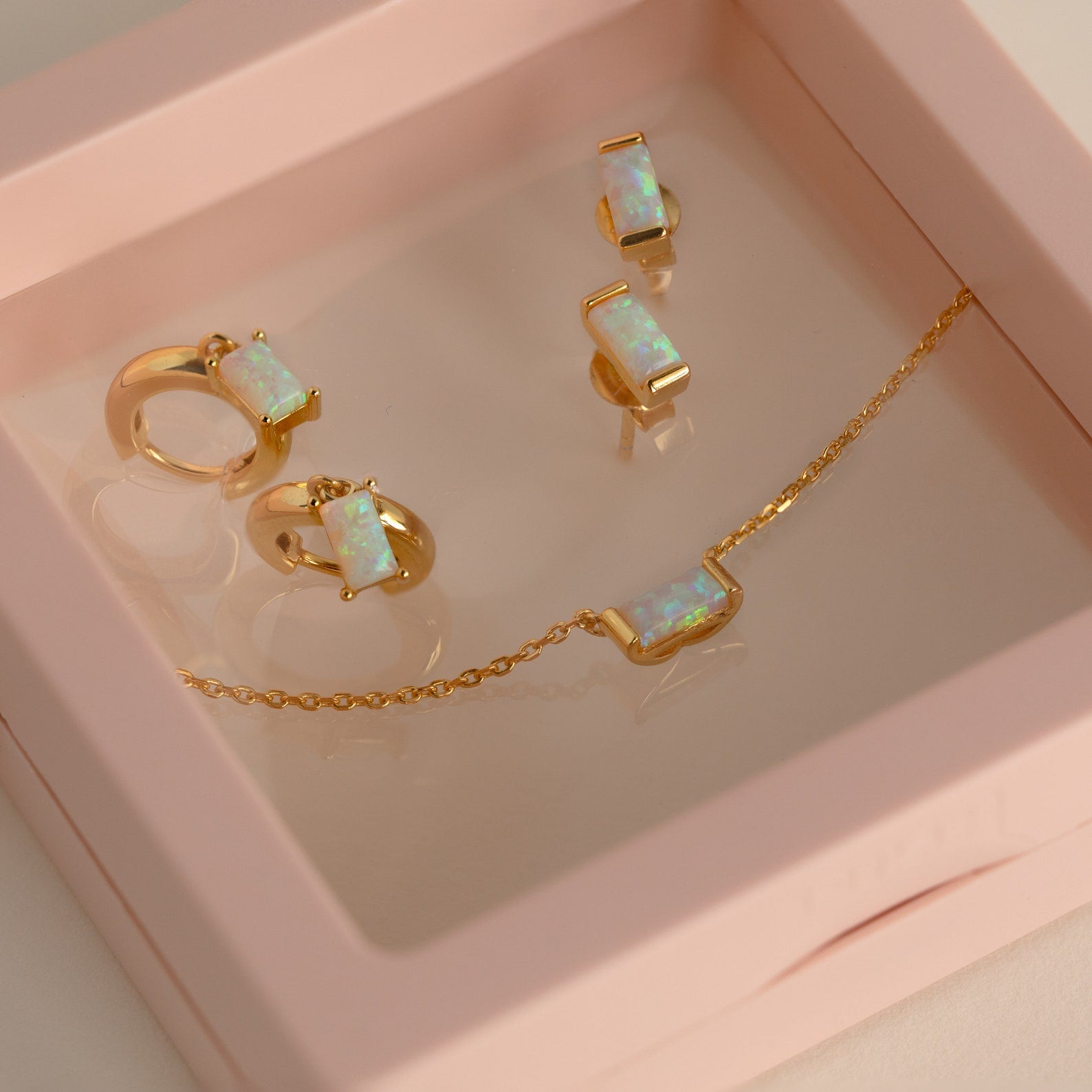 The Birthstone Mystery Box features gold jewelry with opal insets, including a necklace, earrings, and a ring, beautifully packaged for a personalized surprise.