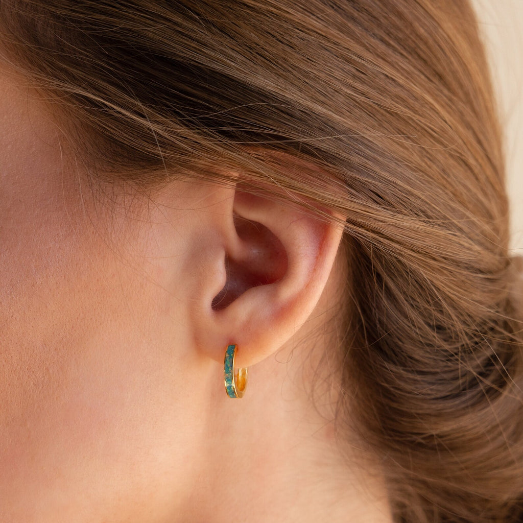 A close-up of a woman's ear with hair pulled back, showcasing the vibrant Green Opal Inlay Hoops.