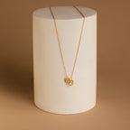 Interlocking Opal Inlay Necklace, symbolizing infinite love, displayed on a white cylindrical stand against a brown background—an elegant anniversary gift.