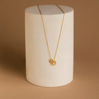 The Interlocking Opal Inlay Necklace and Bracelet Set in 18K Gold, displayed on a white cylindrical stand against a brown background, features interlocking rings and is perfect for pairing together.