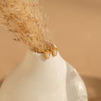 The Dainty Opal Teardrop Studs are displayed on a white vase with dried grass, set against a neutral background.