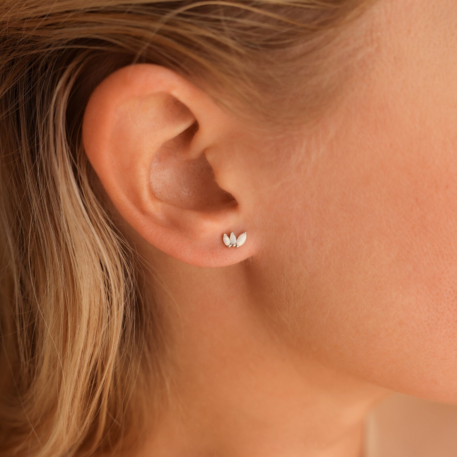 Close-up of a woman's ear wearing the Dainty Opal Stud Earrings Set—small, leaf-shaped silver studs with opal accents. Perfect for minimalist jewelry lovers seeking an elegant, subtle accessory.