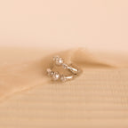 Silver pearl diamond huggie earrings laid on textured ivory fabric, highlighting their refined detail.