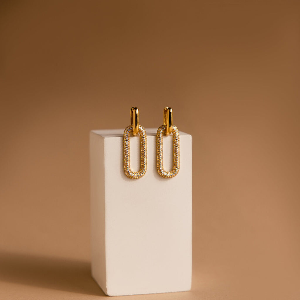 Pave Link Hoops are shown on a white rectangular stand against a brown background.