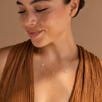 Smiling with her eyes closed in a brown top, she wears the Pave Mom Necklace—a heartfelt treasure with letter charms spelling MOM, perfect for gifting.