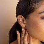 A woman with dark hair wears Lydia Duo Cuffs and touches her ear with manicured fingers.
