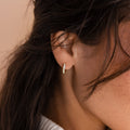 A close-up of a woman's ear wearing the Opal Inlay Hoops Set, accented by her dark hair—an elegant option for bridal jewelry or wedding earrings.