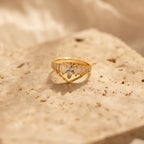 The Art Deco Ring Set, featuring clear gemstones, rests on a textured beige stone surface in soft lighting.