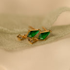 Art Deco Drop Studs feature green gemstone triangles and sparkling CZ diamonds, elegantly displayed on light green fabric.