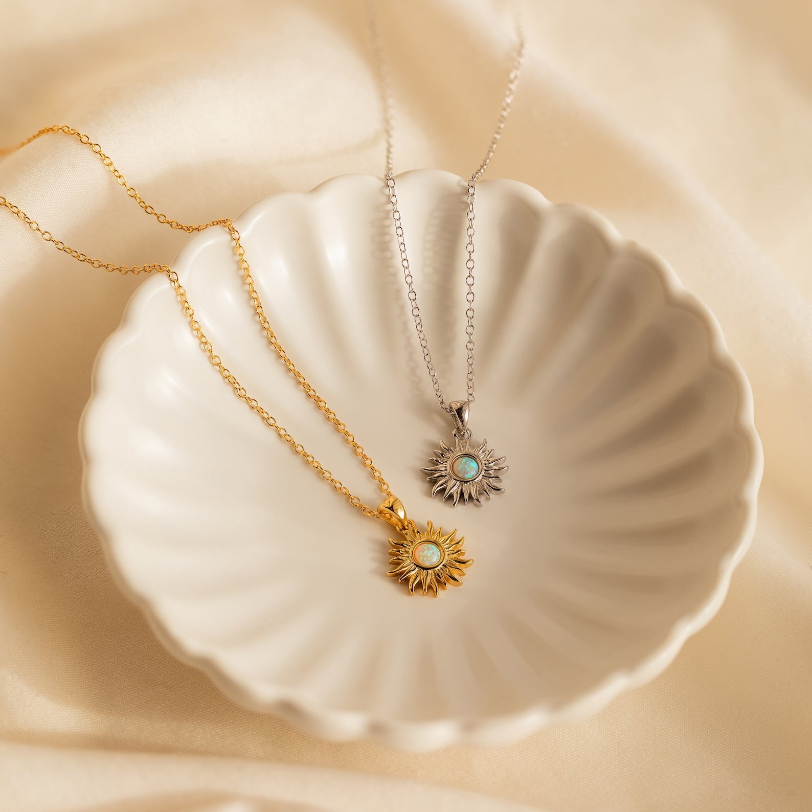 Two Opal Sun Necklaces, one gold and one silver, are displayed in a scalloped dish. This dainty necklace set is a thoughtful jewelry gift.