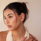 A woman with a scarf around her neck showcases her style, complemented by Opal Chain Earrings from her jewelry collection.