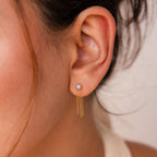 Close-up of a person wearing Opal Chain Earrings—elegant gold drop earrings with opal stone studs, perfect for enhancing any jewelry collection.