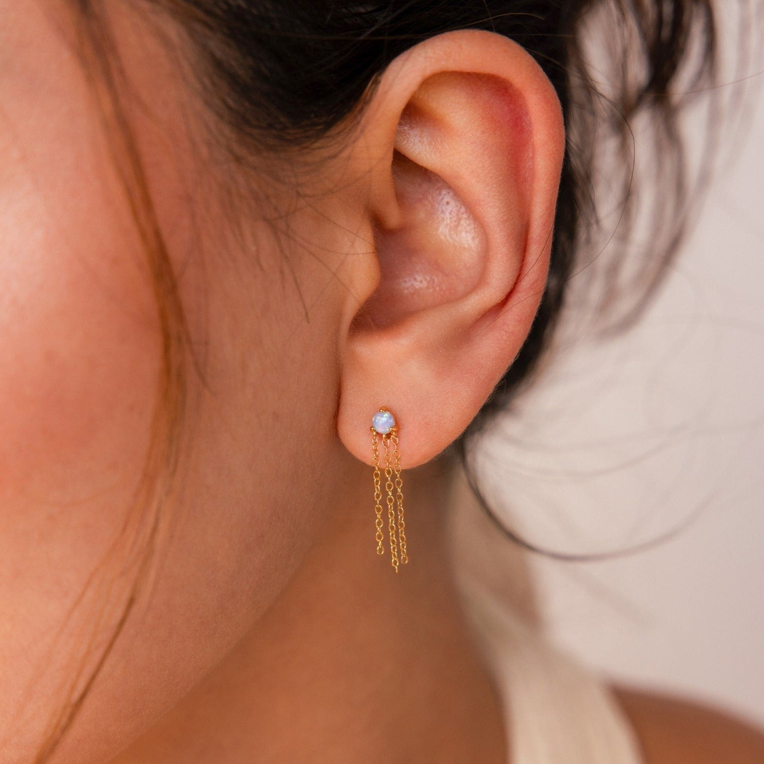 Close-up of a person wearing Opal Chain Earrings—elegant gold drop earrings with opal stone studs, perfect for enhancing any jewelry collection.
