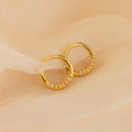 Opal Cartilage Huggies – minimalist gold hoop earrings with delicate opal gems, perfect for cartilage or everyday wear, shown on soft beige fabric.