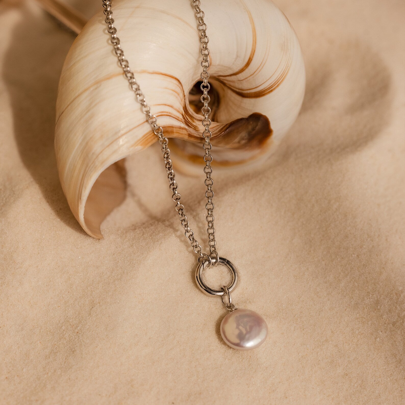 The Round Pearl Charm in Silver is a timeless necklace with a round Mother of Pearl pendant, inspired by the ocean—perfect for adding subtle elegance to any look.