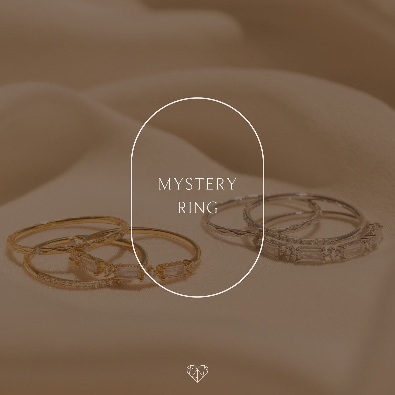 Two sets of gold and silver Mystery Rings from our unique jewelry collection rest on soft beige fabric, with "Mystery Ring" displayed in the center.