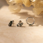The Agate Cartilage Earrings Set features three silver earrings with green gemstones, displayed on beige with dried flowers—an ideal gift for best friends or a stylish choice for cartilage piercings.