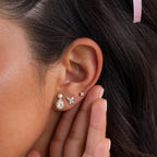 Close-up of a woman's ear adorned with Pearl Diamond Teardrop Studs, as her hand gently touches her ear.