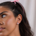 A woman with a pink ribbon in her hair wears elegant Pearl Diamond Teardrop Studs, featuring shimmering pavé diamond detailing.