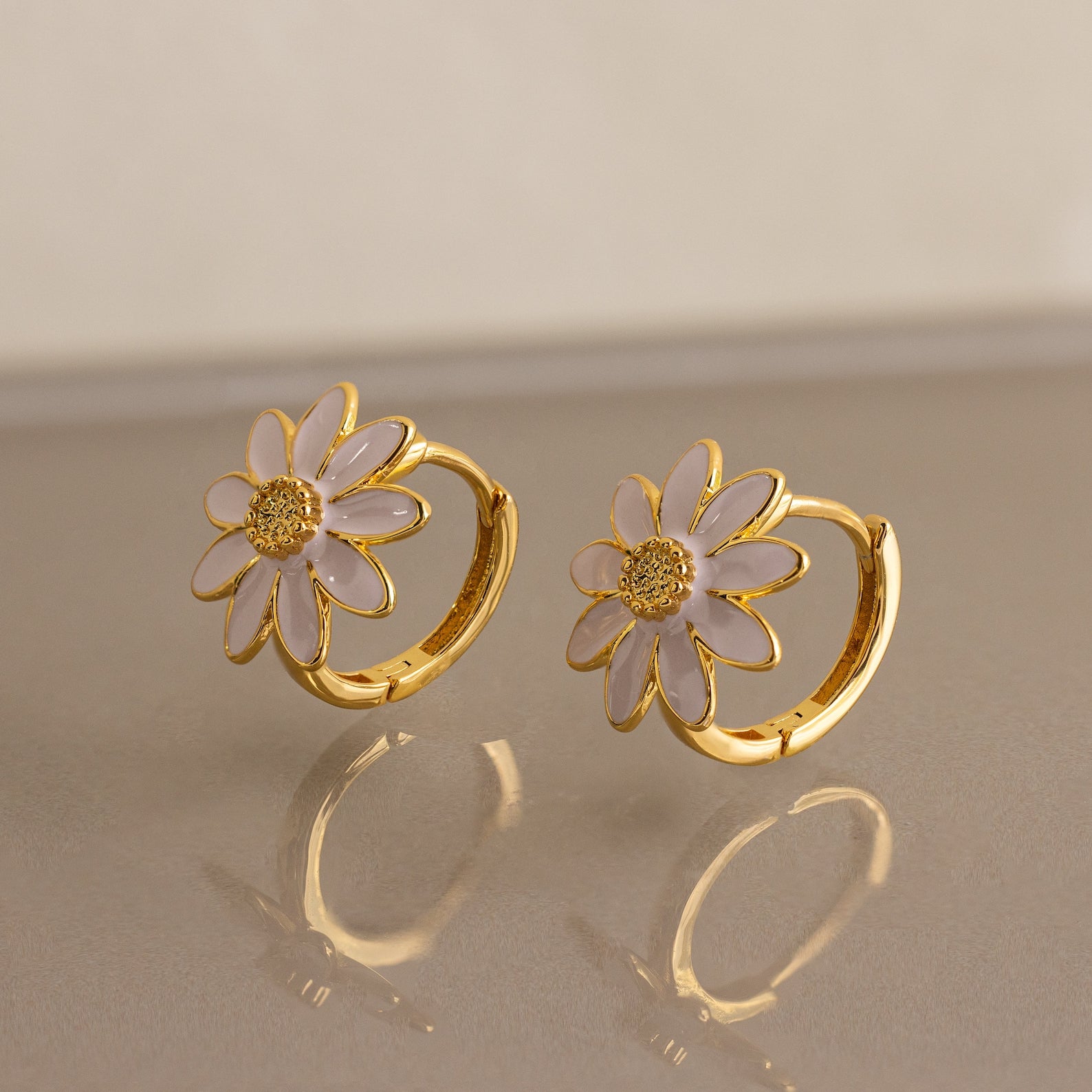 Daisy Huggies earrings bring minimalist floral elegance to any outfit.