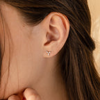 Close-up of a woman’s ear wearing the Trio Floral Marquise Studs, a gold set featuring three small stones.