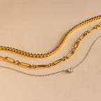 Three necklaces from the Mystery Necklace Box on a beige background: two gold chains and one delicate silver chain with a small pendant—ideal for your jewelry collection or as a special surprise.