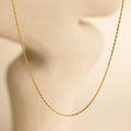 The Skinny Mariner Chain Necklace is shown on a soft, blurred beige background with minimal curves—an elegant, minimalist piece perfect for everyday wear and layering.
