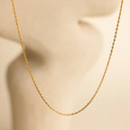 The Skinny Mariner Chain Necklace is shown on a soft, blurred beige background with minimal curves—an elegant, minimalist piece perfect for everyday wear and layering.