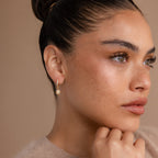 Woman with smooth skin and freckles wears a gold hoop earring and the Opal Star Necklace & Earrings Set in 18K Gold, gazing thoughtfully to the side.