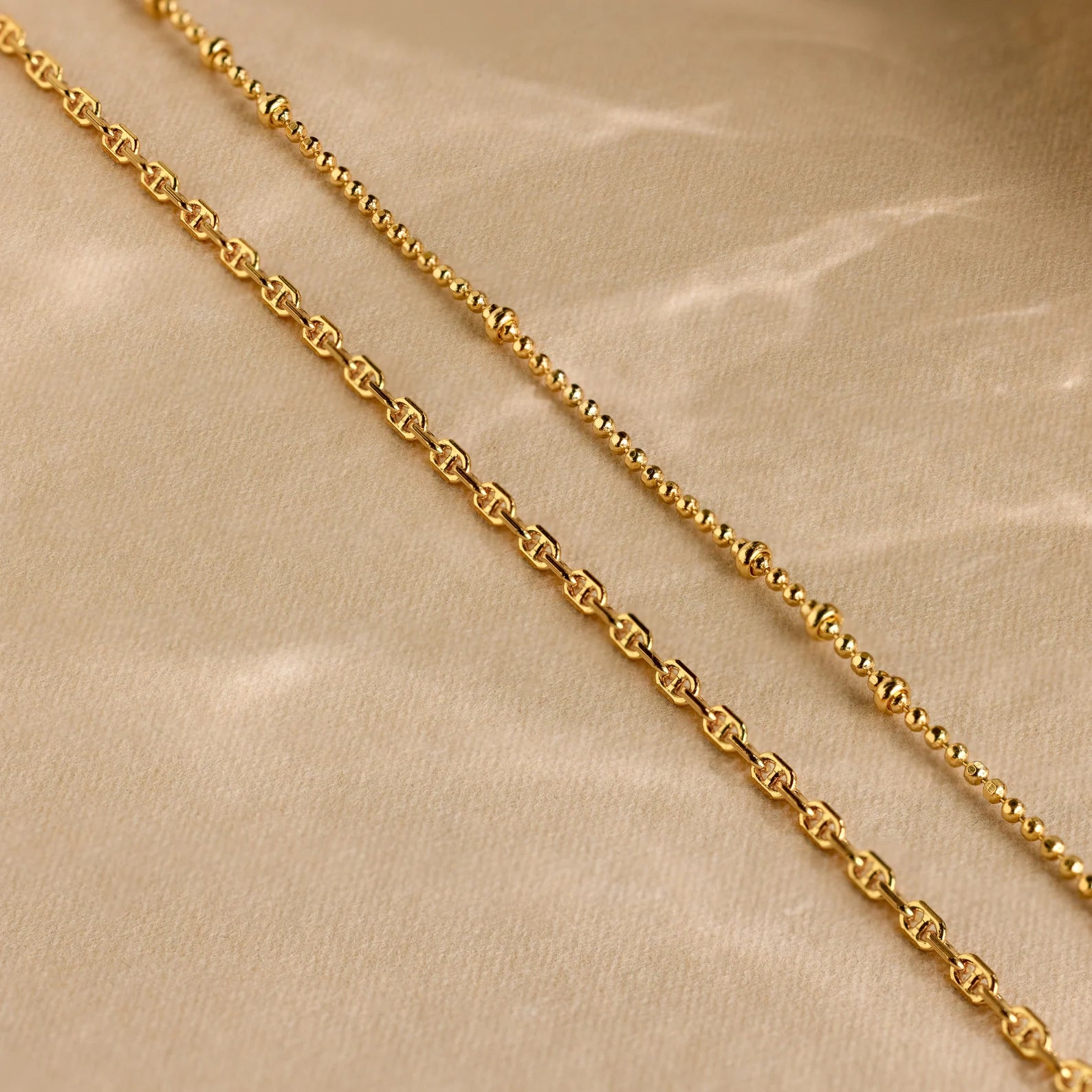 The Skinny Mariner Chain Necklace shines on a beige fabric background—ideal for an elegant layered look or as a stylish everyday necklace.