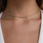 A close-up of a person wearing the Dainty Diamond Necklace Set—a delicate tennis choker featuring small, closely set diamonds—against bare skin and a white top.