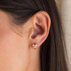 Close-up of a woman's ear wearing Diamond Ribbon Bow Huggies, featuring a small gold hoop with a decorative bow design.