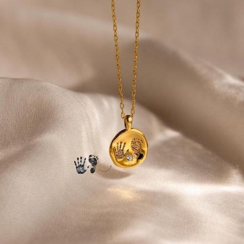 The Baby Handprint Coin Necklace displays a delicate handprint and footprint design, making it a perfect new mom gift and personalized keepsake to celebrate those first precious moments.