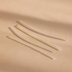 Four transparent, coiled Ring Size Adjusters are arranged diagonally on a beige surface under soft lighting.