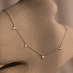 Sterling Silver Heart Station Necklace & Bracelet Set with small heart-shaped charms displayed on a beige textured mannequin bust.
