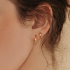 A close-up of a woman's ear adorned with Editor Huggies in Rose Gold, showcasing a minimal aesthetic.