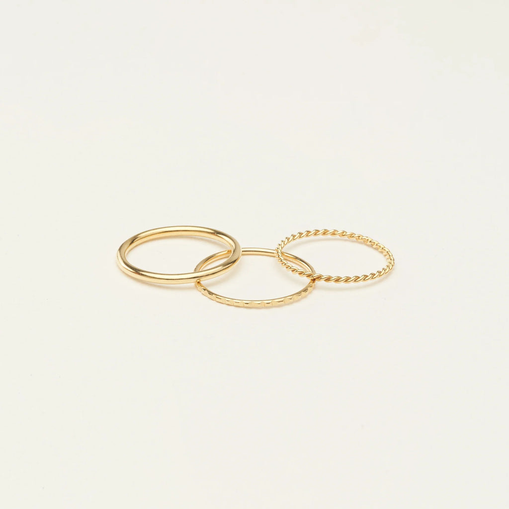 The Thin Stacking Rings Set in 18K Gold features three textured rings, ideal for creating a chic layered look on any light background.