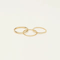 The Thin Stacking Rings Set in 18K Gold features three textured rings, ideal for creating a chic layered look on any light background.