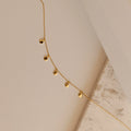 The Onyx Necklace Set features delicate gold necklaces with small round charms, displayed on a neutral textured surface—ideal for layering and adding a subtle touch to your minimalist style.