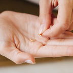 Close-up of hands holding small gold star earrings with diamonds.
