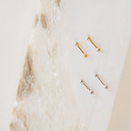 The Nora Duo Studs in Sterling Silver—featuring two gold and two silver ball studs—are displayed on textured white marble, making them the perfect classic earrings for your everyday style.